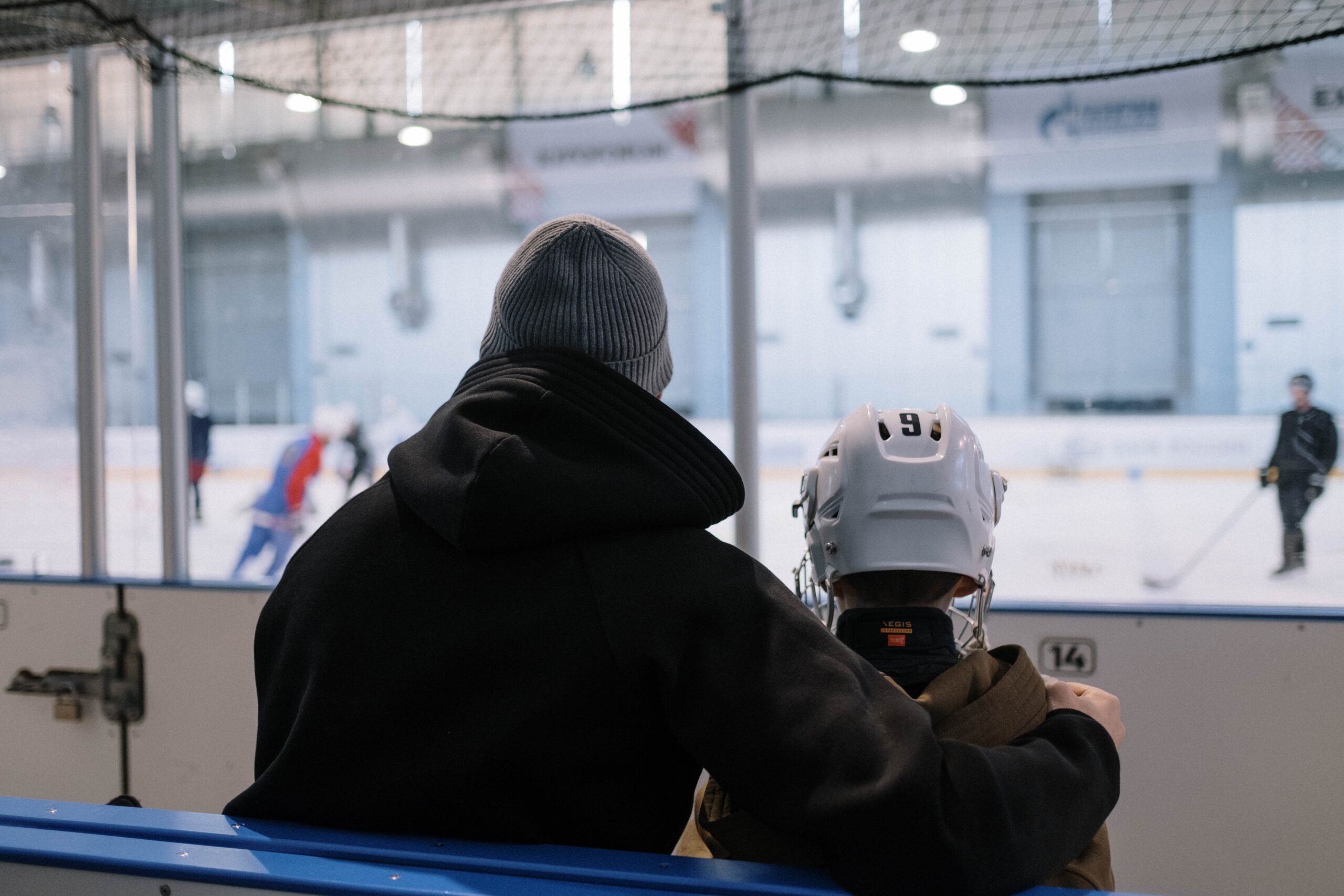 En vuxen håller an arm runt en ung hockeyspelare.